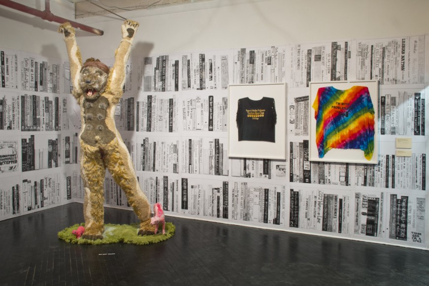 Installation view: Foreground: Lady Sasquatch (Bunny) (2006-2010); Found textiles, taxidermy supplies, appliqué borg, styrofoam, wood. Recommended Reading (2010); Wallpaper of photocopied drawings. Both by Allyson Mitchell and courtesy of the artist and Katharine Mulherin Gallery, Toronto. I’m With Problematic / Women’s Studies Professors Have Class Privilege, from the series Creep Lez, (2012): Altered t-shirts with iron-on transfer and vinyl letters Courtesy of the artist and Katharine Mulherin Gallery, Toronto. Image courtesy of Vox Populi.